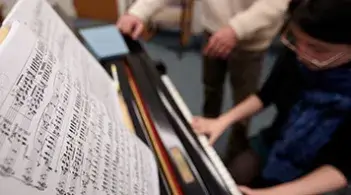 Person playing the piano from sheet music.