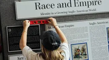 Person installing a "Race and Empire" exhibition display.