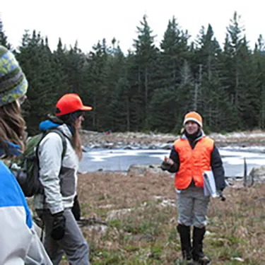 A group of people standing in a field with a lake in the background