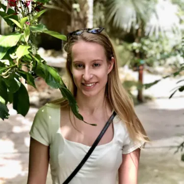 A student in a white shirt standing next to plants
