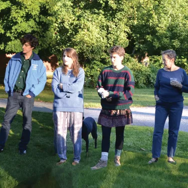 Group of people with a dog standing in a circle.