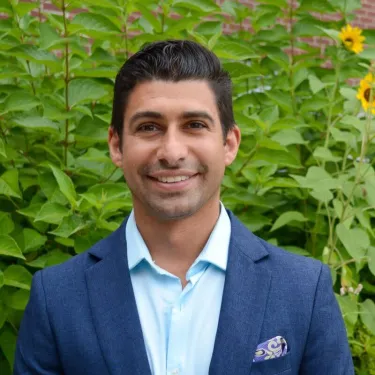 Headshot image of the researcher outdoors, posed in front of green foliage