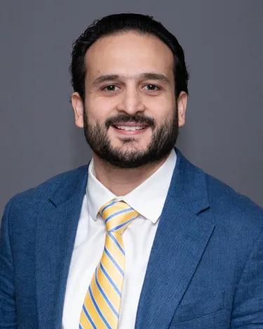 Researcher smiling posed against a grey background