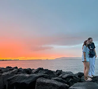two students by the water at sunset