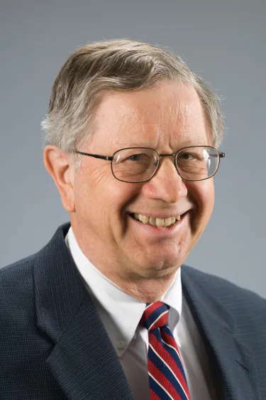 A person wearing glasses, a blazer, and a tie