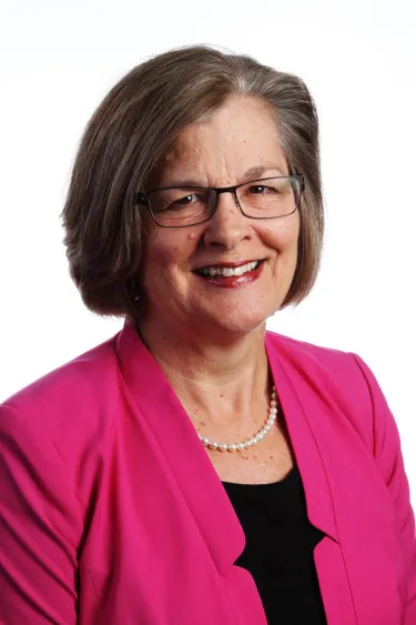 A person wearing glasses and a pink blazer