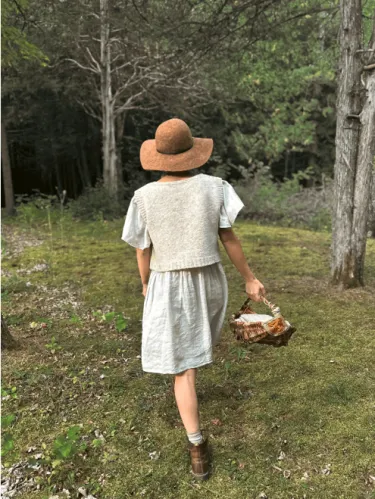 Woman walking into the woods wearing hemp sweater vest
