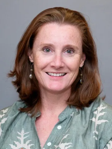 A person wearing a buttoned shirt and earrings