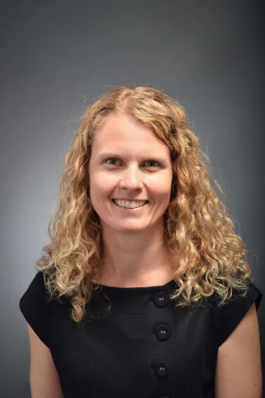 A person with curly hair wearing a dark shirt