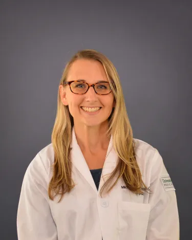 A person wearing glasses and a white coat