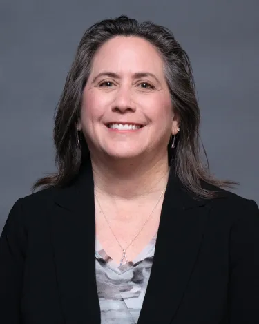 A person wearing a blazer and a necklace