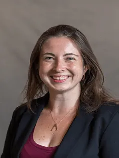 A person wearing a blazer and a necklace