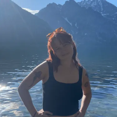 Headshot of Simone standing in water in front of mountains