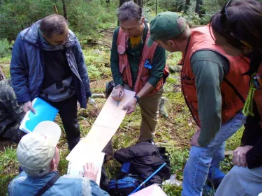 People standing in a circle holding a paper. 