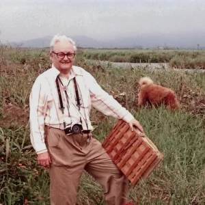 Countryman in the field with plant press and dog