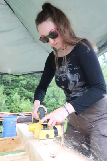 UVM student intern uses a belt sander to build a pavilion at a community park in the Northeast Kingdom