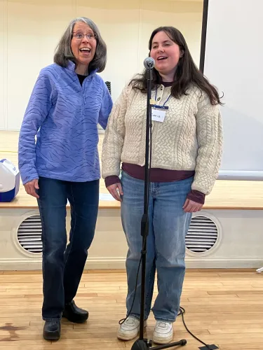 Aphasia Choir director and student singing on stage