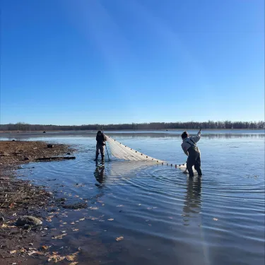 Nina and a classmate casting a drag net into a body of water.