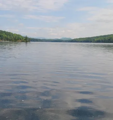 Water in a resevoir with land on sides and mountains in distance 