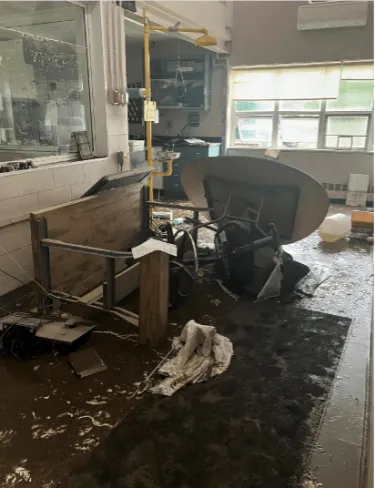 A photograph showing a room strewn with debris and inundated with raw sewage.