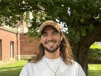 Person wearing a baseball cap and smiling outdoors.