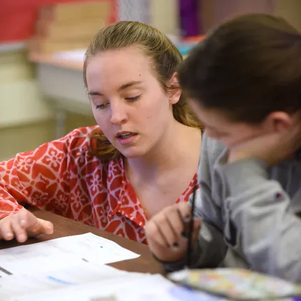 Student helping another with a math equation
