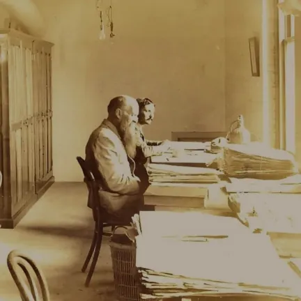 Pringle and Lozano sitting at a table of specimens with cabinets in background
