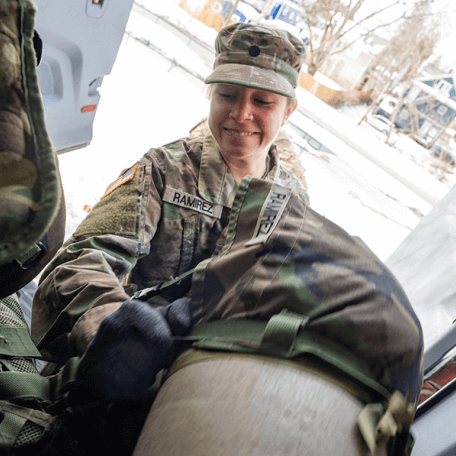 A woman wearing fatigues loads a van