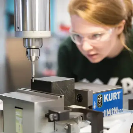student inspects machinery equipment close up