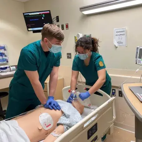 UVM nursing students practice lifesaving CPR techniques on a mannequin during training