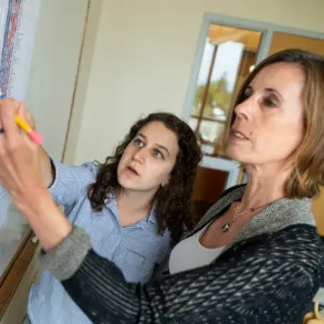 Two people writing on a board