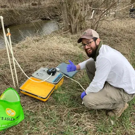 Maxwell using field equipment next to a river.