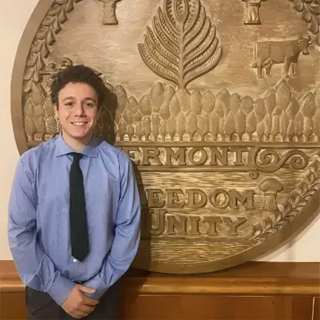 A image of a person in blue shirt and black tie standing in front of a wall