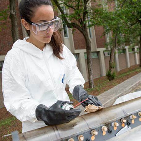ME student cleaning research device outside of Votey Hall