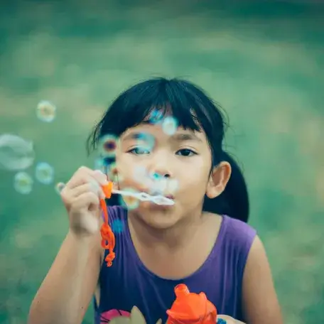 young child blowing bubbles towards the camera
