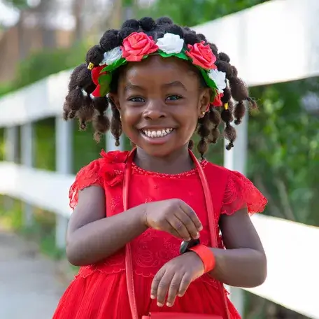 young child with flowers in her hair smiling at the camera