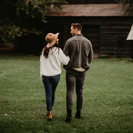 a happy couple arm in arm walking towards a barn