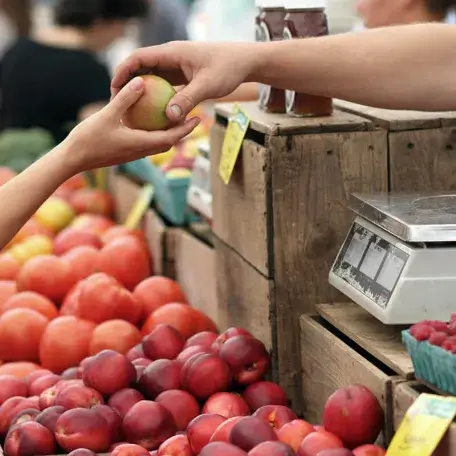 a customer handing a piece of fruit to a shopkeeper