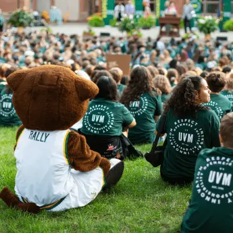Group of students and a mascot sitting on grass