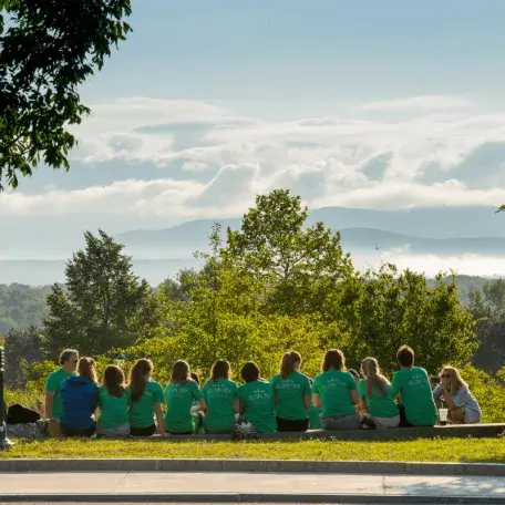 Students sitting in a group outside on the grace with mountains and trees in the background
