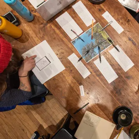 View looking down on a table with students working collaboratively in a writing workshop