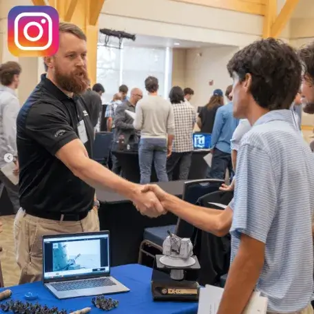 Student and tech company rep shake hands