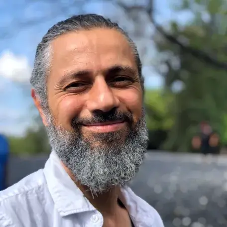 headshot photo of Mohamad, smiling with blurred background of trees and blue sky