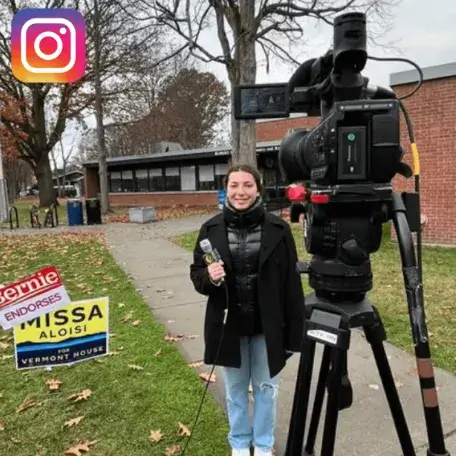 Student holding a microphone in front of a news camera