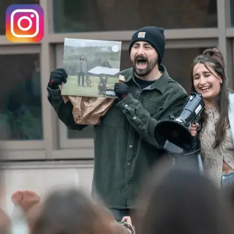 Man holds up Noah Kahan's Stick Season album