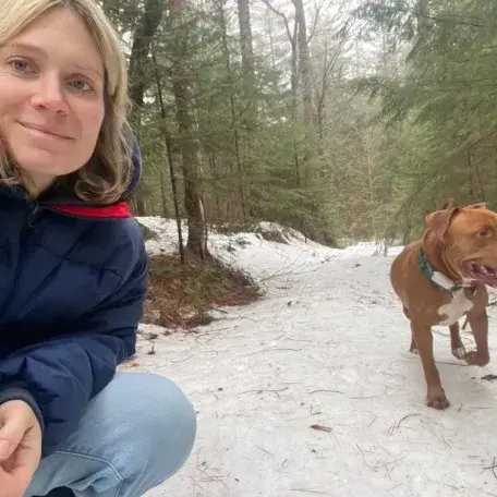 Dru kneeling in a snowy forest with her dog