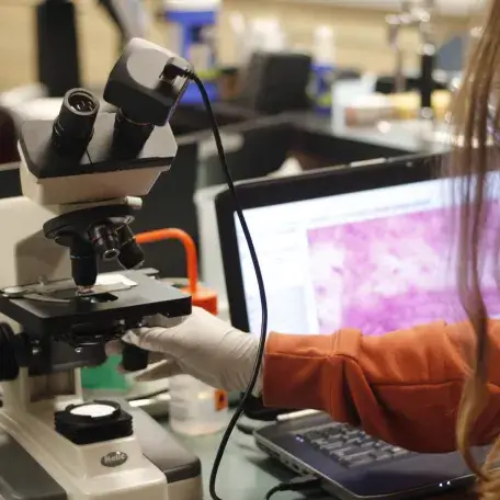 Image of student working with research microscope in lab