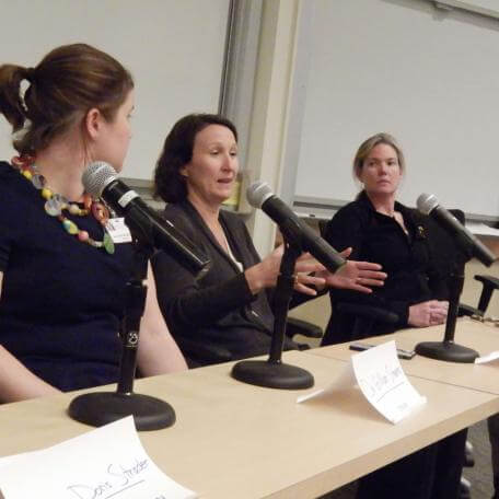 Three people at a table speaking into microphones