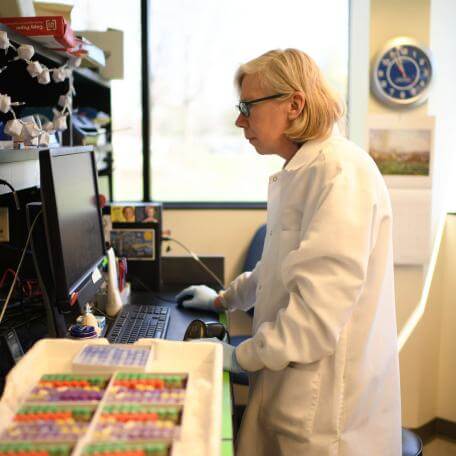 Scientist looking at computer next to test tubes