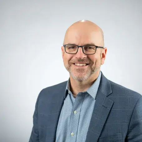 A person wearing glasses and a blazer